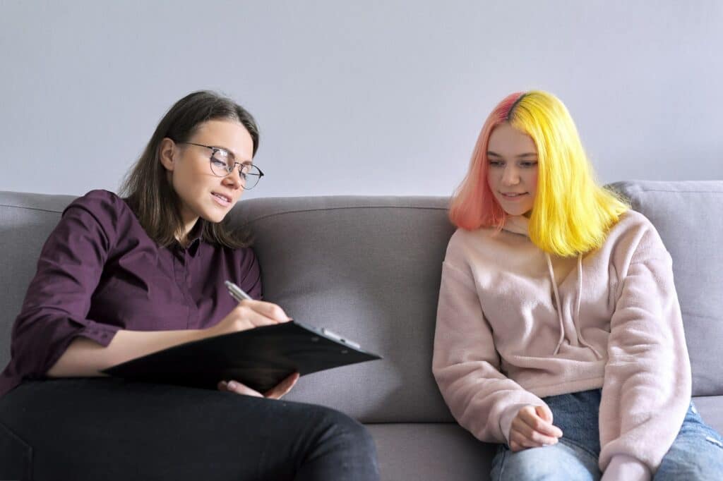 Woman psychologist working with teen girl. Visit and counseling of professional therapist