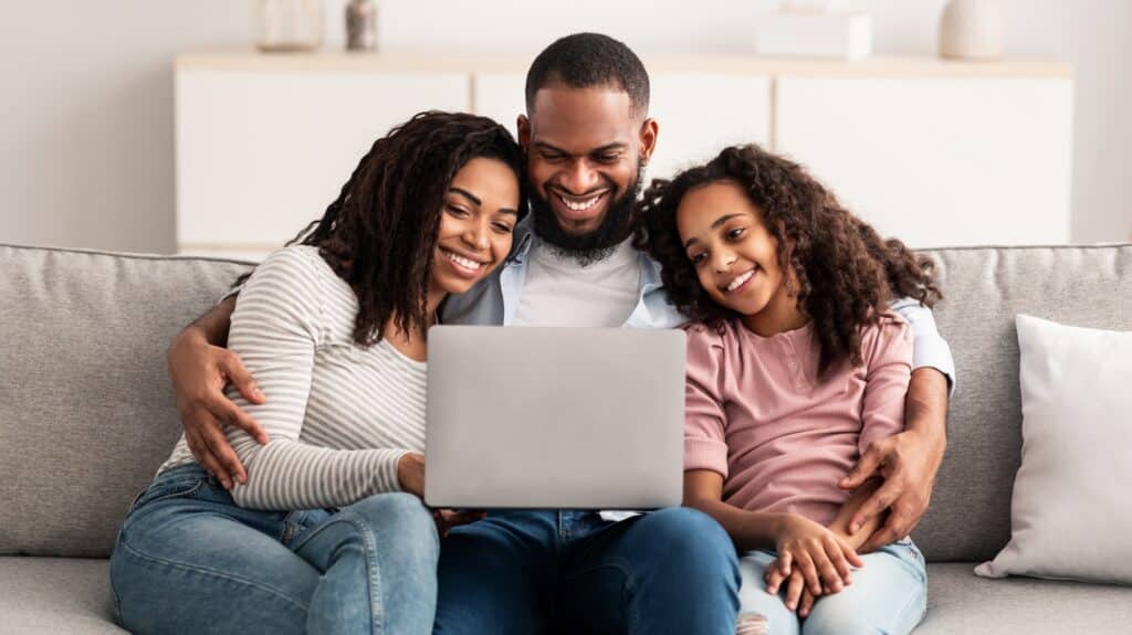 Happy black family using laptop in living room
