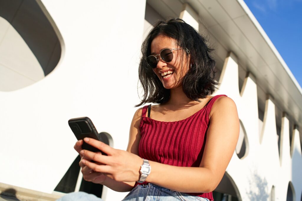 Woman Smiling and Using Mobile Phone Outdoors. Happy People smartphone.